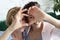 Mother and daughter love. Adult woman and young woman stacking hands in heart sign looking at camera.