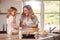 Mother And Daughter Making Pancakes In Kitchen At Home Together