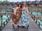 mother and daughter in matching tropical dresses standing together on wooden bridge pathway, women on vacations