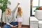Mother and daughter measuring child height writing mark on wall at home