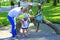 Mother with daughter near metallic sculpture of children and turtle in city park