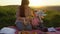 Mother and daughter on a picnic on a hill in the summer at sunset.