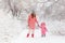 Mother and daughter in pink down jackets in winter