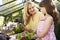 Mother And Daughter Planting Hanging Basket In Greenhouse