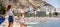 Mother and daughter on the Postiguet beach at summer, rear view. Mother showing to the Santa Barbara castle