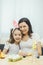 Mother and daughter preparing for Easter, painting eggs, hugging. Child in bunny ears.