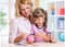 Mother and daughter putting coins into piggy bank