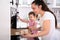 Mother And Daughter Putting Tray With Cookies To Oven