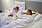 Mother and daughter relax in bed watching TV.