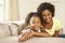 Mother And Daughter Relaxing On Sofa At Home