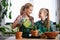 Mother and daughter repotting plants together at home garden