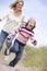 Mother and daughter running on beach smiling