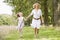 Mother and daughter running on woodland path