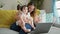 Mother and daughter\\\'s smiling moment, relaxing on sofa while engaging in a family video call using laptop at home. maternity love