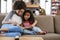 Mother And Daughter Sit On Sofa In Lounge Reading Book Together