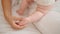 Mother and daughter sitting on bed together touching feet at bedroom