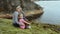 Mother and daughter sitting on the big stones on the sea shore