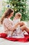 Mother and daughter sitting at Christmas tree