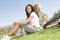 Mother And Daughter Sitting On Grass In Park