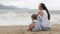 Mother with a daughter sitting with his back to the camera on the sandy beach.