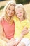 Mother And Daughter Sitting On Straw Bales In Harv