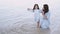 Mother and daughter sitting in the water on a beach