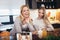 Mother and daughter with smartphone having breakfast and taking selfie at home kitchen