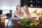 Mother and daughter with smartphone having breakfast and taking selfie at home kitchen