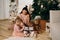 Mother and daughter in stylish beige clothes unfold New Year`s gifts under the tree. christmas midnight celebration concept