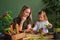 Mother and daughter take care of green plants in the room of the house, replant and lead a healthy lifestyle, spend home leisure