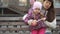 Mother and daughter take sefi while sitting on a bench near a busy road.