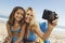 Mother And Daughter Taking Self Portrait On Beach