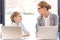 Mother and daughter talking while sitting at table with laptops