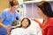 Mother And Daughter Talking To Female Nurse In Hospital Room