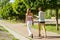 Mother and daughter teenager walking through the city park on a summer sunny day.