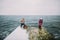 Mother and daughter with their little pet dog walking on the old pier. Winter holidays, sea background