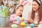 Mother and daughter together easter preparation at home sitting in bunny ears mixing color close-up