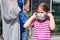 Mother and daughter together, little girl putting on or taking off protective anti viral medical face mask. Family shopping