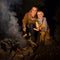 Mother and daughter travellers near campfire grilling sausages