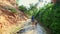 Mother daughter walk along shady fairy stream backside view