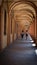 Mother and daughter walking through arched portico in a summer day