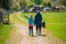 Mother and daughter walking a dog along a country track while the little girl points at something that interests her