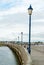 Mother and daughter walking dog along old English wooden jetty lined with street lamps