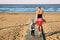 Mother and daughter walking by wooden flooring on sand beach at seaside. Summer family vacation. Children care and support by pare