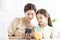 Mother with daughter watching the mobile phone and checking the piggy bank for her future savings
