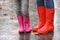 Mother and daughter wearing rubber boots after rain, focus of legs.