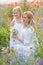 Mother and daughter in white dresses among the flowering meadows