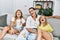 Mother and daughters smiling confident sitting on sofa at home