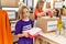 Mother and daughters wearing volunteer uniform holding folded clothes working at charity center