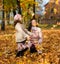 Mother and daugter playing with fallen yellow leaves. Portrait of a happy people in an autumn park